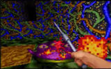 Screenshot from Ultima Underworld II of the player wielding a steel weapon against purple creature. The background has a wall with inscrutable, colorful designs.